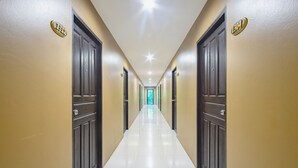 Un couloir d’hôtel avec des portes numérotées 1312 et 1304, menant à une sortie bien éclairée.