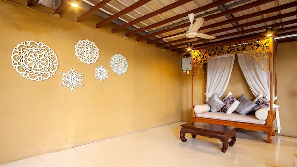 A room with a wooden four-poster bed, a small table, and decorative wall art. - Naiyang Beach Hotel (Sa Khu)