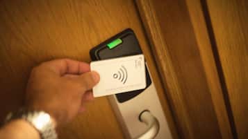 Une main tenant une carte blanche sur laquelle figure un symbole de signal sans fil, posée sur une porte dotée d’un indicateur lumineux vert.