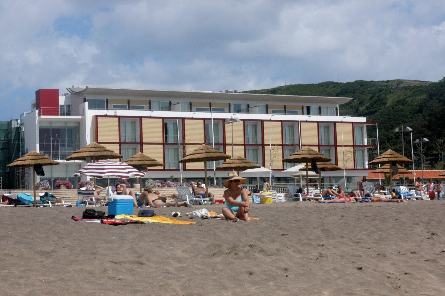 Um hotel à beira-mar com vários quartos, guarda-sóis e espreguiçadeiras.