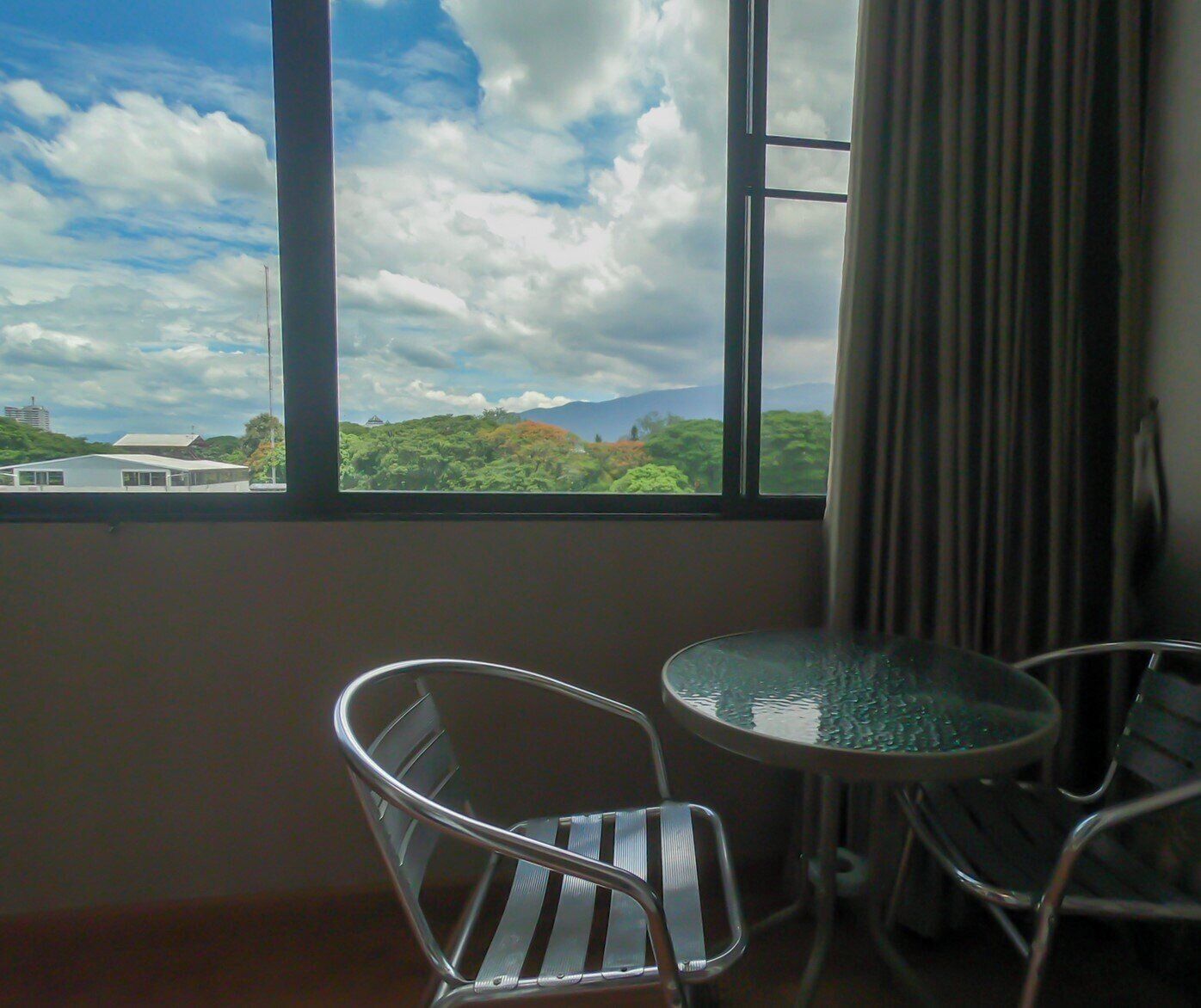 A room with a large window, a round table, and two chairs.