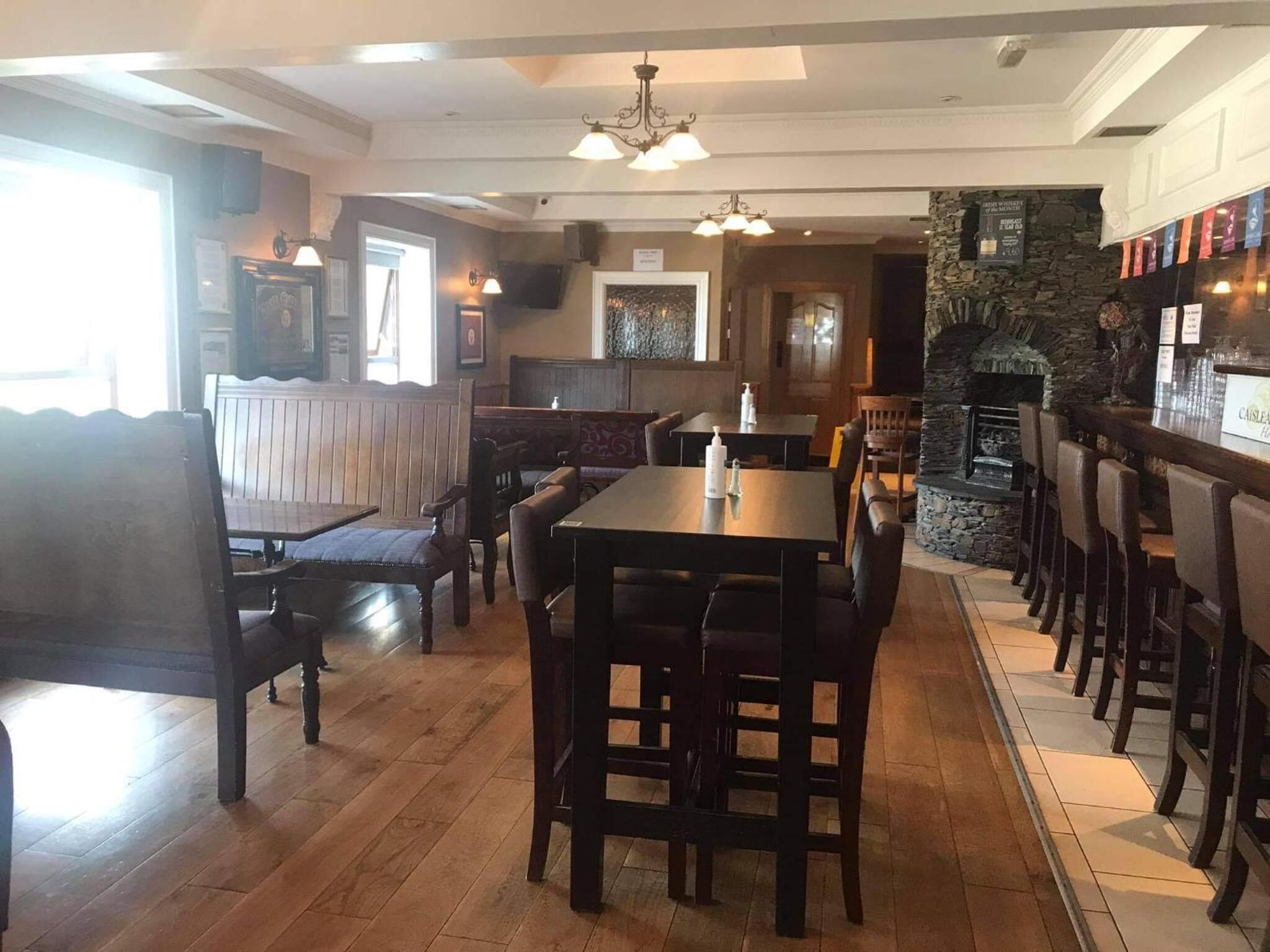 Interior de restaurante con mesas y bancos de madera, detalles de piedra y una chimenea.