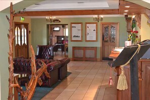 A cozy lobby with a wooden bench, a television, and a reception desk. - Caisleain Oir Hotel (Annagry)