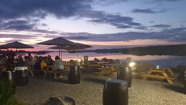 Un espace aménagé avec des tables et des parasols, situé au bord du lac et offrant une vue sur une étendue d’eau paisible.