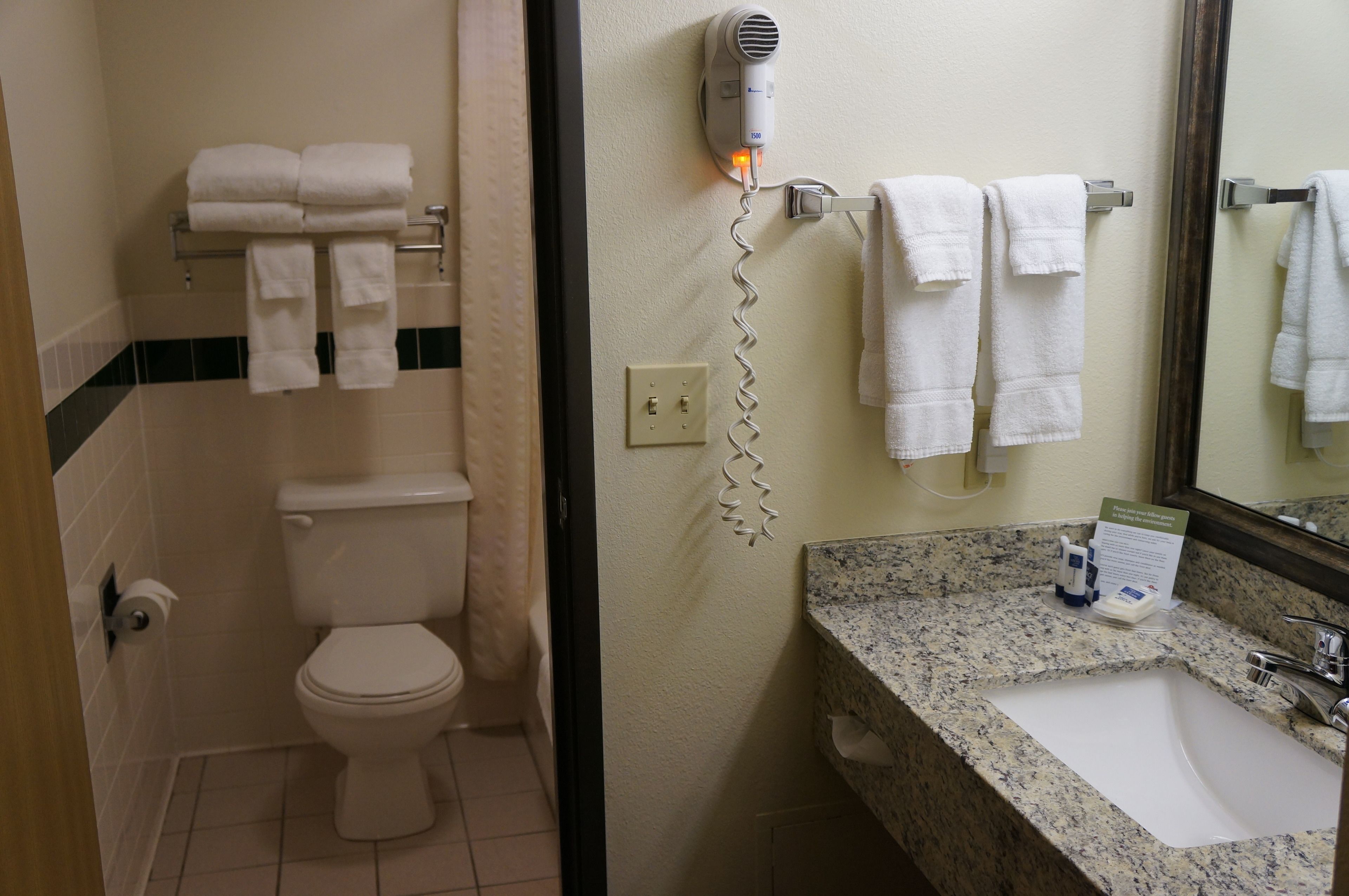Casa de banho com sanita, porta-toalhas, secador de cabelo e lavatório.