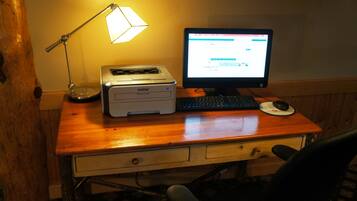 Un escritorio de madera con una impresora Brother, un monitor de computadora, un teclado y un ratón.