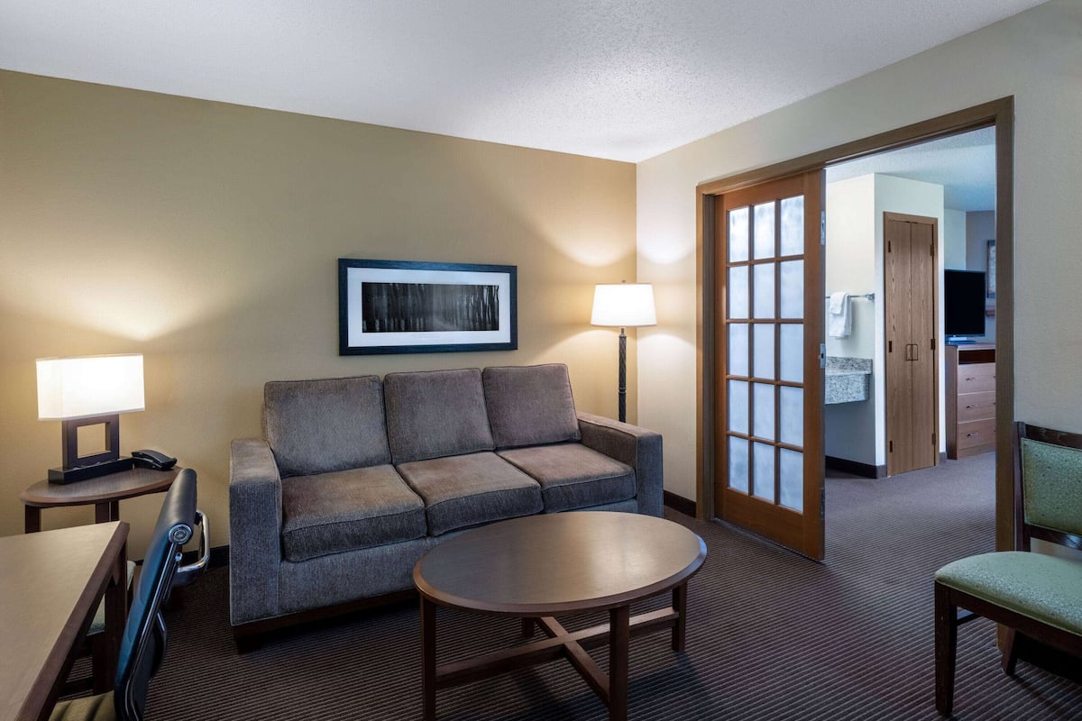 Une chambre d’hôtel avec un canapé, une table ronde, une lampe et un téléviseur.