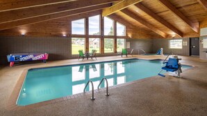 Une piscine intérieure avec des poutres en bois, une table de billard et des chaises.