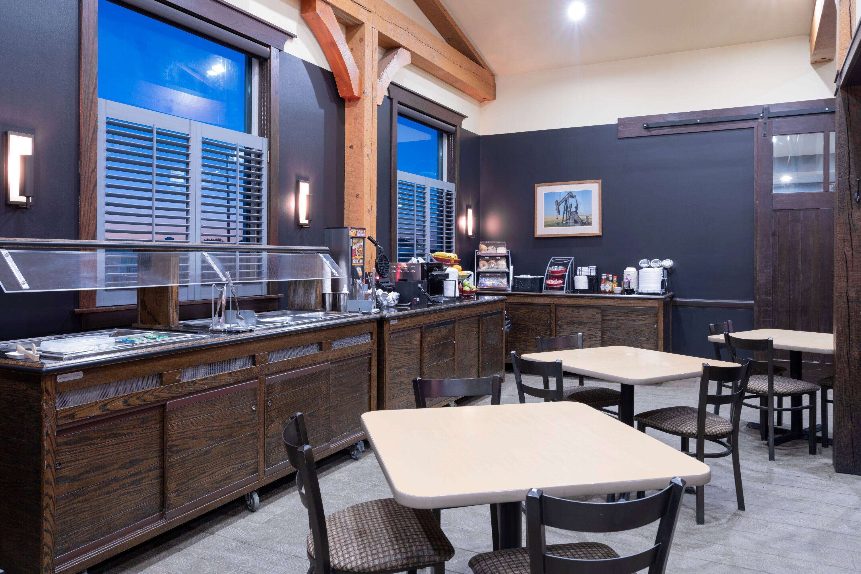 A restaurant with a wooden counter, tables, and chairs.