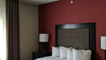 A hotel room with a large bed, red walls, and two bedside lamps.
