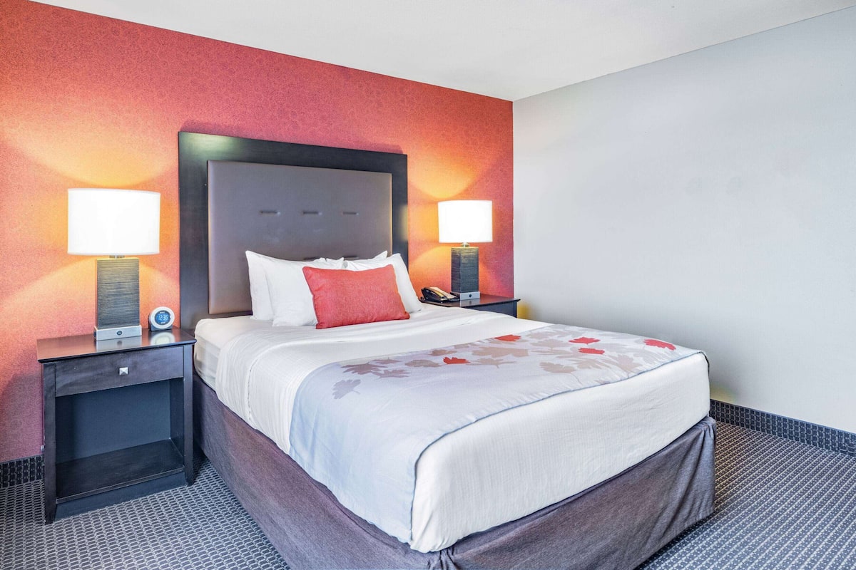 Quarto de hotel com uma cama grande, duas mesas de cabeceira e uma cabeceira.