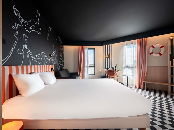 A modern hotel room with a large bed, a desk, and a chair. There is a black and white striped wall and a black ceiling. - ibis Styles La Rochelle Centre les Minimes (La Rochelle)
