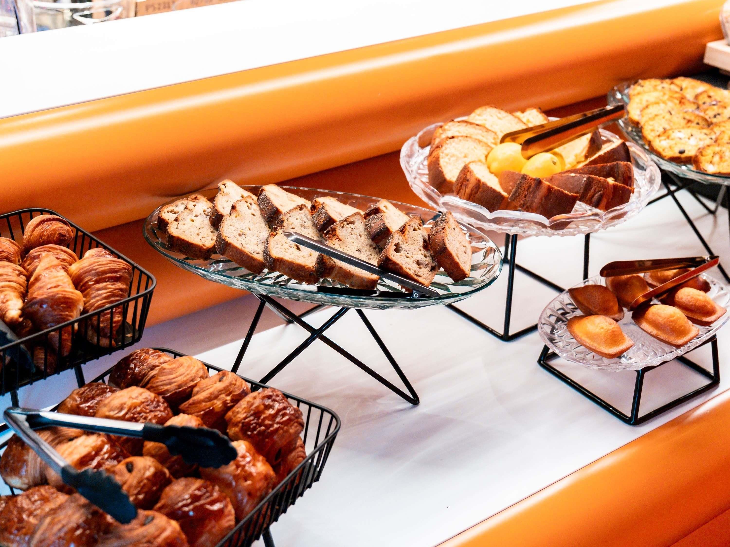 A buffet with various baked goods including bread, pastries, and cakes.