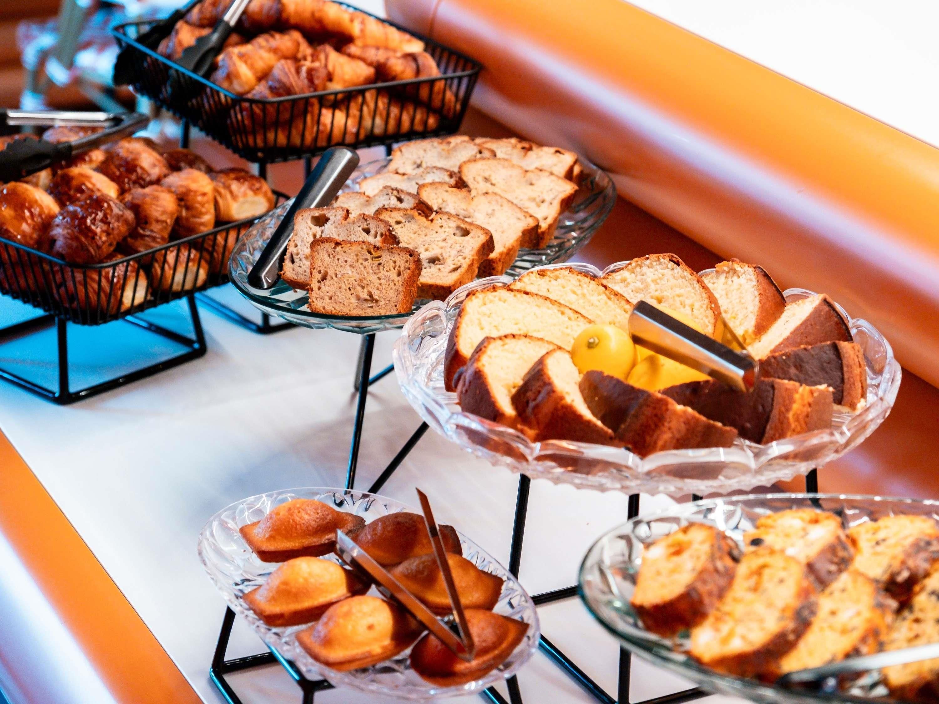A buffet with various baked goods including bread, muffins, and cakes.