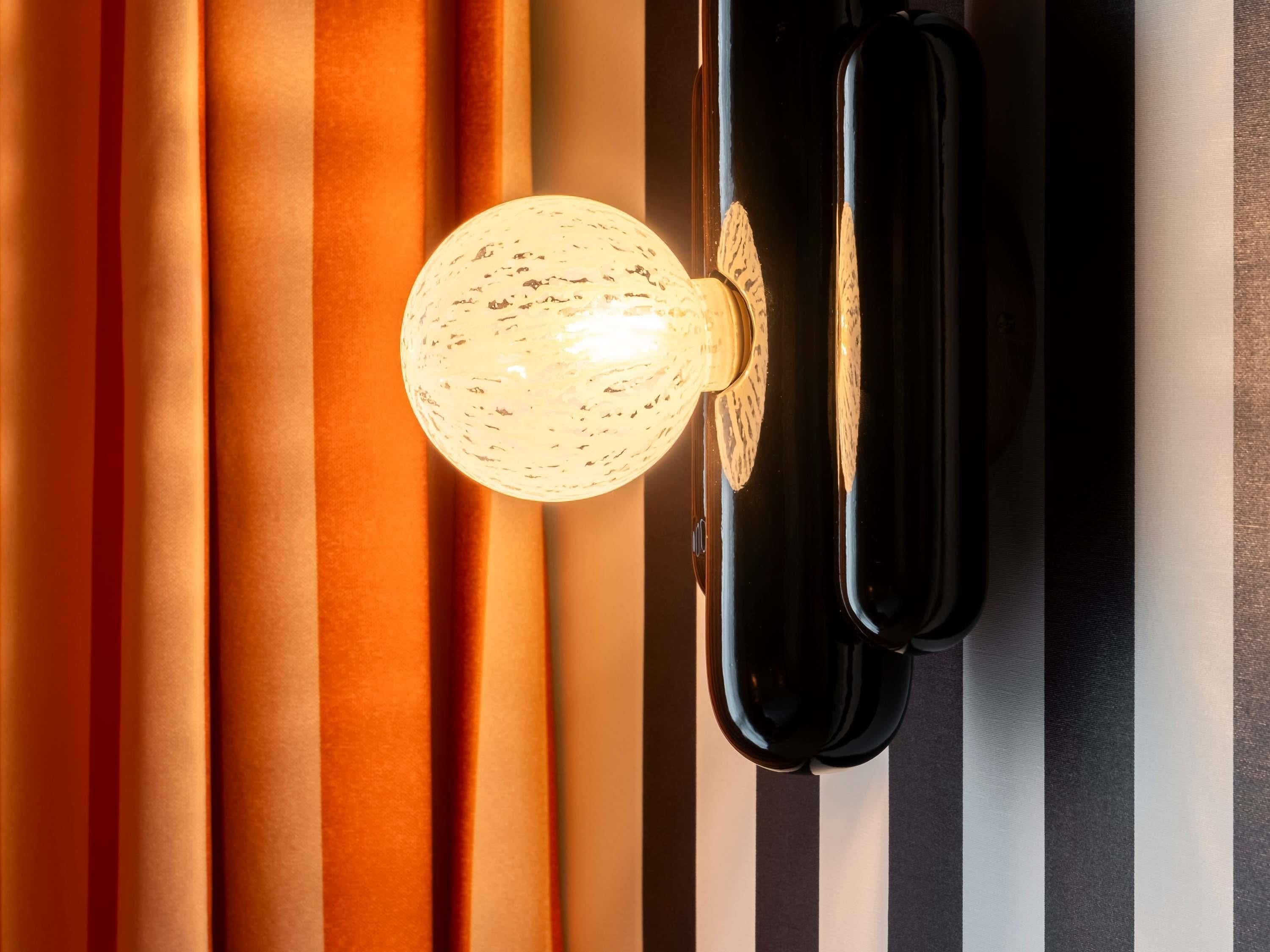 A wall with vertical stripes in various colors and a spherical light fixture.