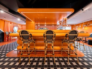 A bar area with a checkered floor, orange seating, and a bar counter with taps. - ibis Styles La Rochelle Centre les Minimes (La Rochelle)