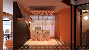 A reception area with a patterned desk, a check-in counter, and a view of the outdoor seating area. - ibis Styles La Rochelle Centre les Minimes (La Rochelle)