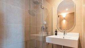 A modern bathroom with a glass-enclosed shower, a white sink, and a large mirror. - ibis Styles La Rochelle Centre les Minimes (La Rochelle)