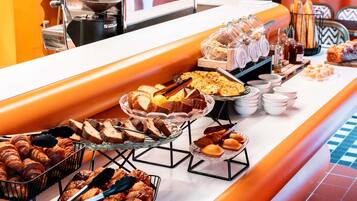 A buffet with various food items including bread, pastries, and a coffee machine.