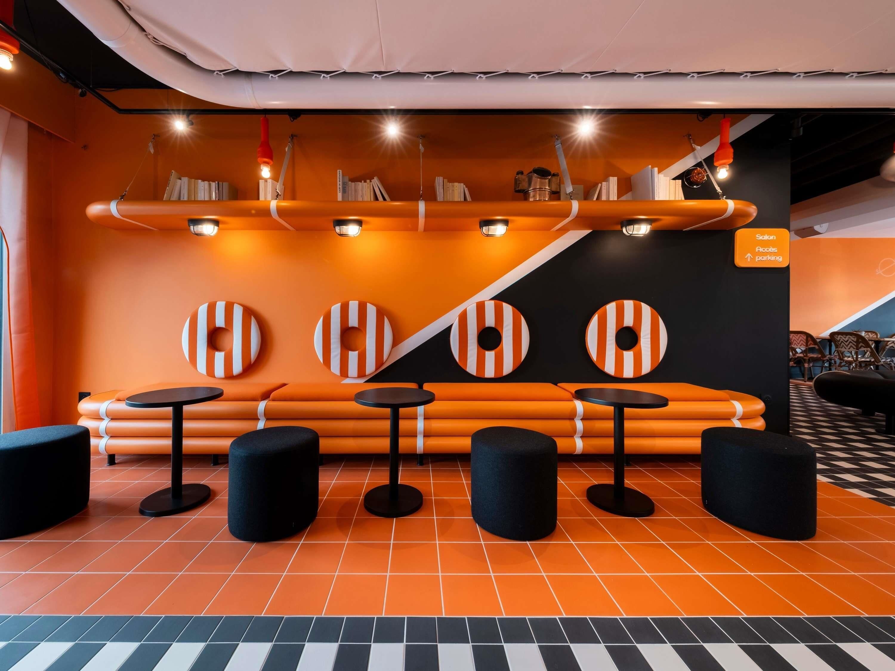 A modern lounge area with orange seating, black stools, and a checkered floor.