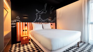 A modern hotel room with a large bed, striped headboard, and a checkered floor. - ibis Styles La Rochelle Centre les Minimes (La Rochelle)
