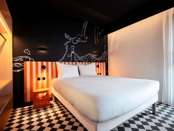 A modern hotel room with a large bed, striped headboard, and a black and white checkered floor. - ibis Styles La Rochelle Centre les Minimes (La Rochelle)