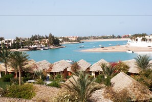 Une station balnéaire dotée de cabanes aux toits de chaume, d’un port de plaisance et d’une plage.