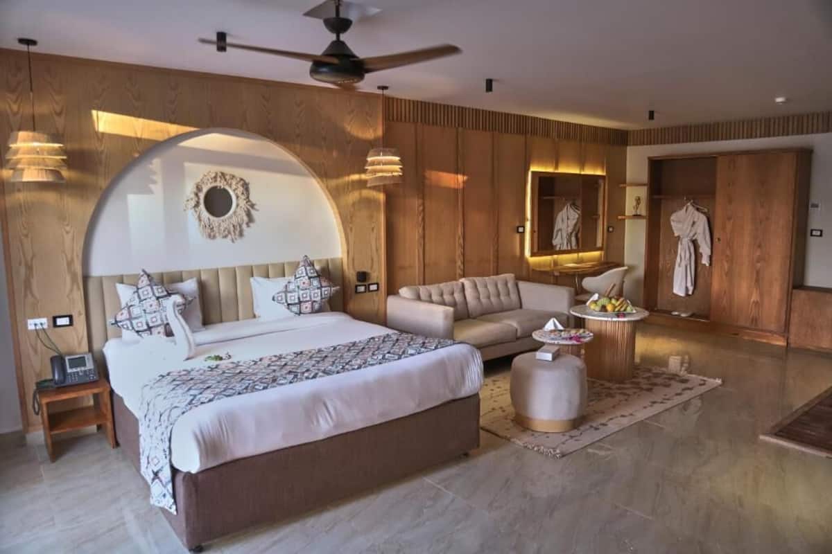 Een moderne slaapkamer met een groot bed, een bank, een ronde salontafel en een kledingkast.