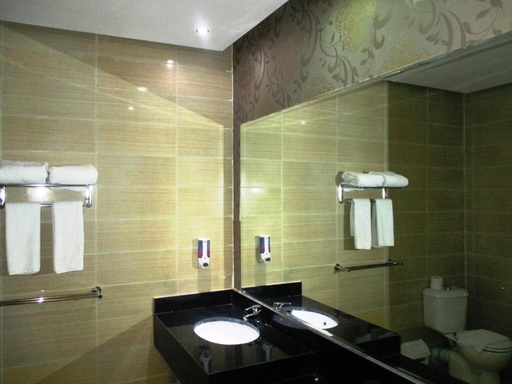 A modern bathroom with two sinks, a large mirror, and a toilet.