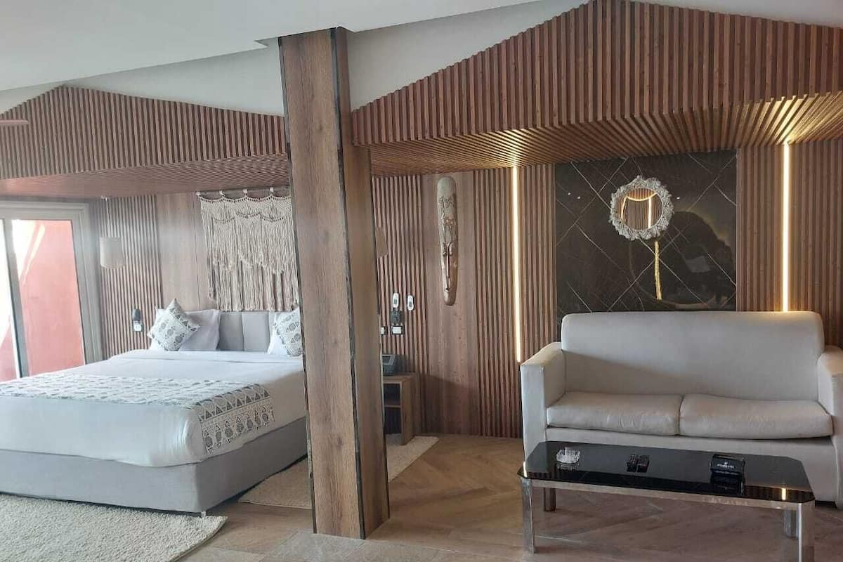 Een moderne slaapkamer met een bed, een bank en een bijzettafeltje.
