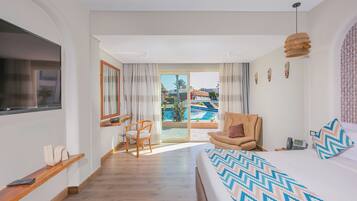 A hotel room with a bed, a chair, a TV, a desk, a phone, and a view of a pool.