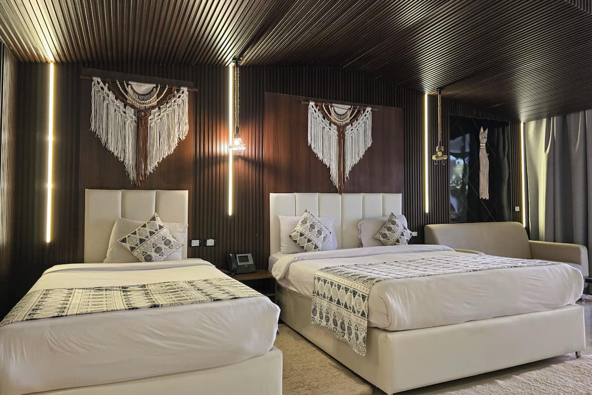 Een moderne hotelkamer met twee bedden, een sofa en een grote spiegel.