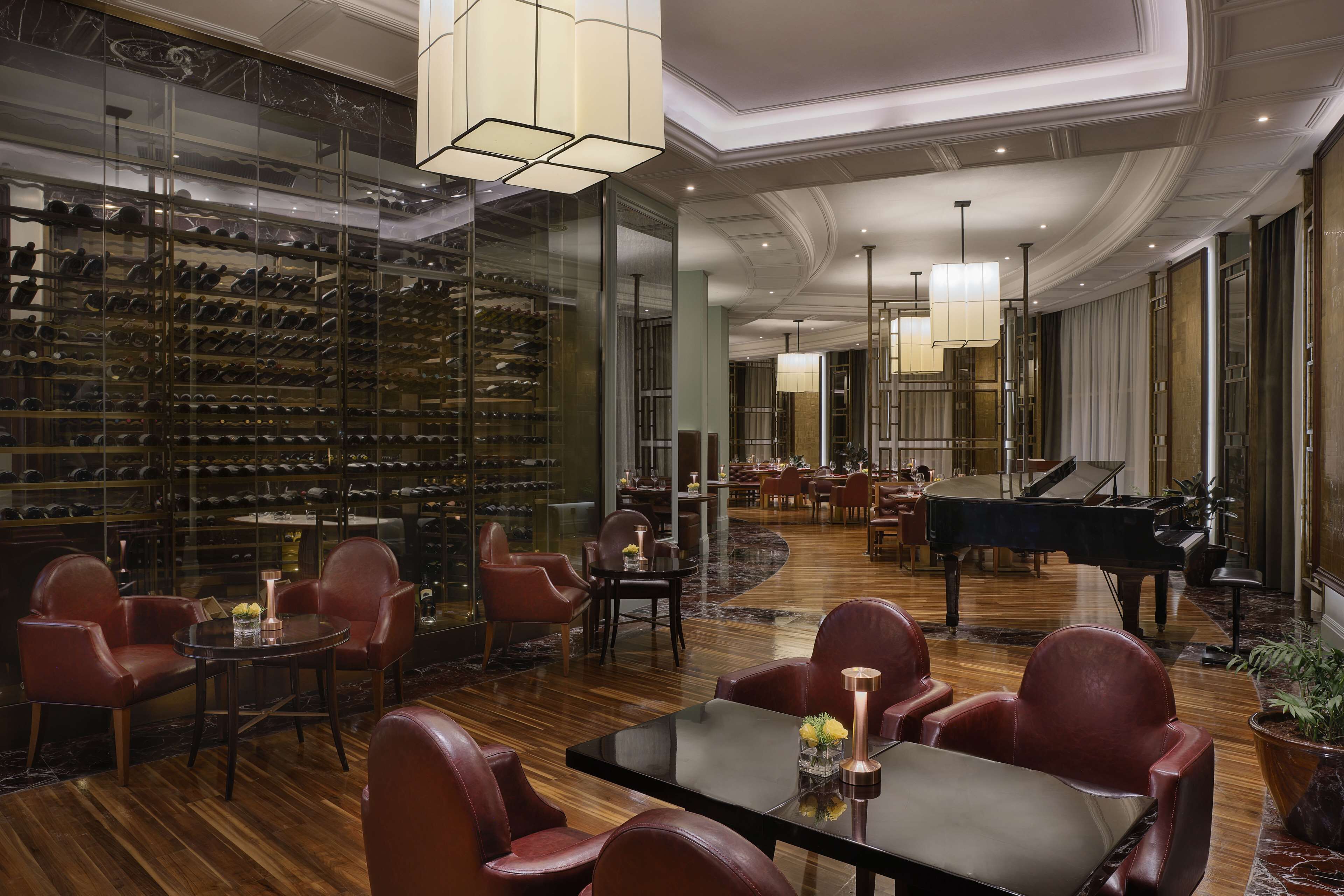 Un hall d’entrée luxueux agrémenté d’une cave à vin, de fauteuils en cuir, d’un grand piano et d’élégants lustres.