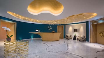 A modern reception area with a curved wooden desk, a marble floor, and a unique ceiling design.