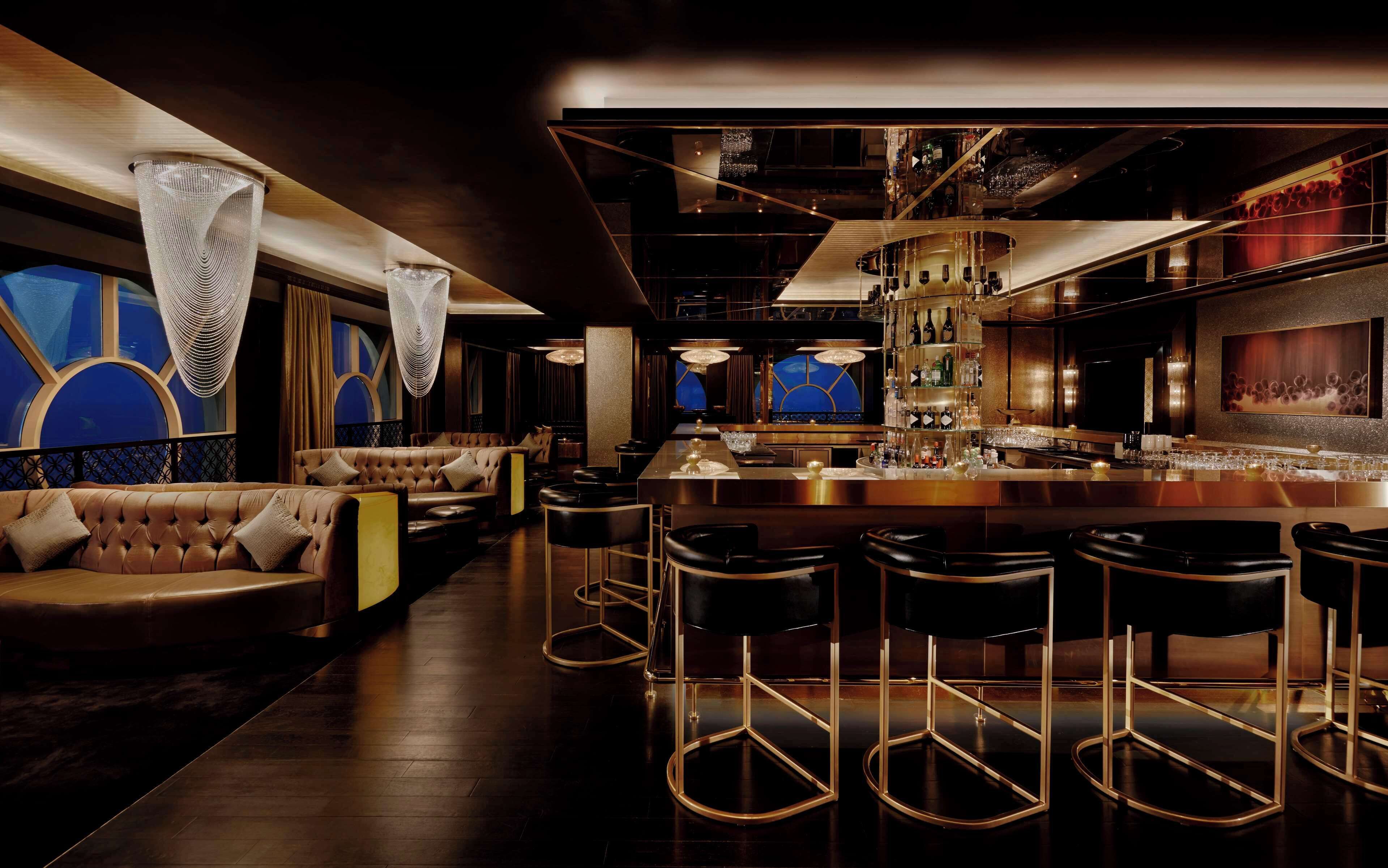 A bar area with a long counter, bar stools, and a seating area with a sofa and chairs.