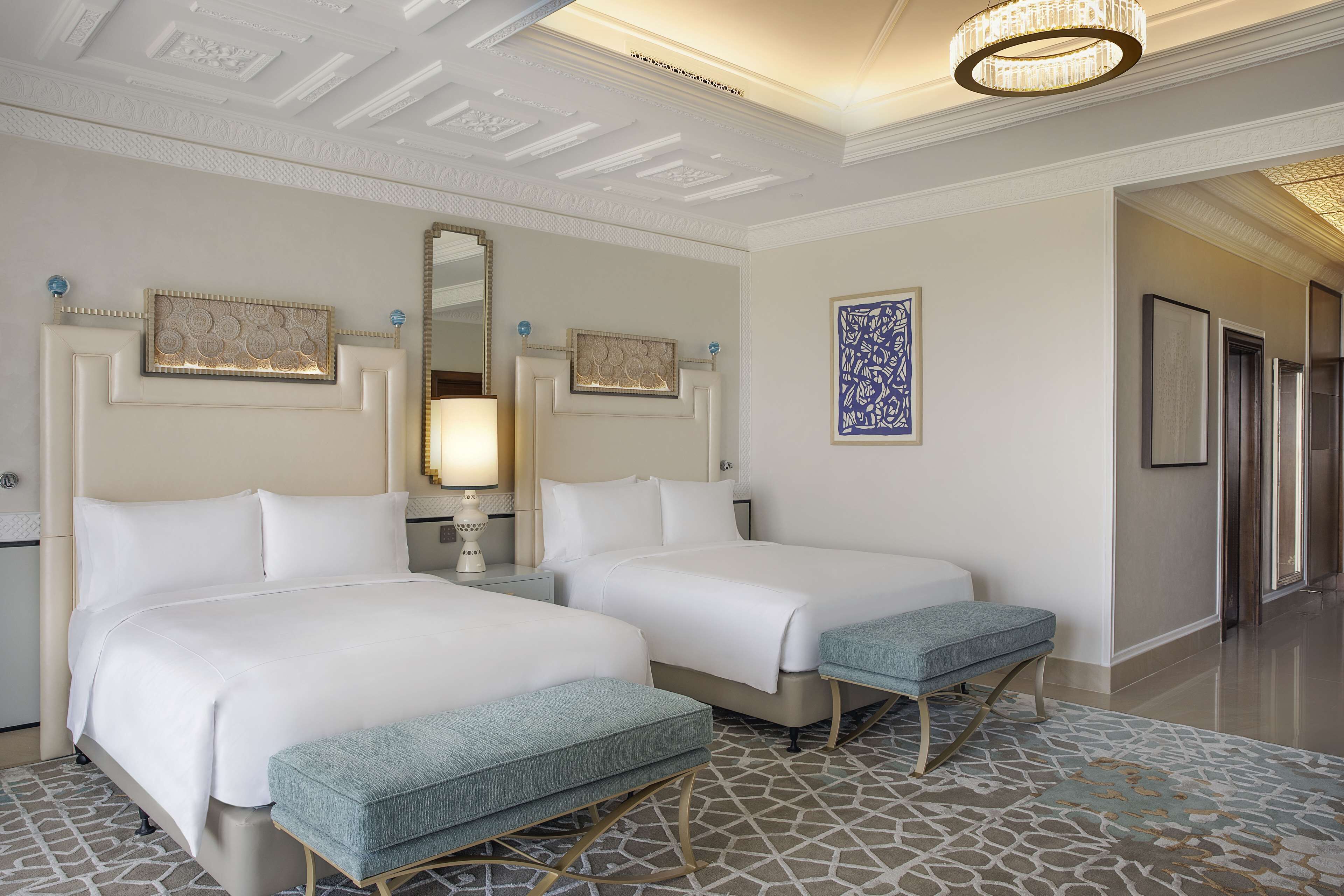 A hotel room with two beds, a large mirror, and a patterned rug.