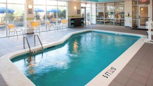 An indoor swimming pool with clear water, a lifeguard chair, and a sign indicating a 5ft depth.