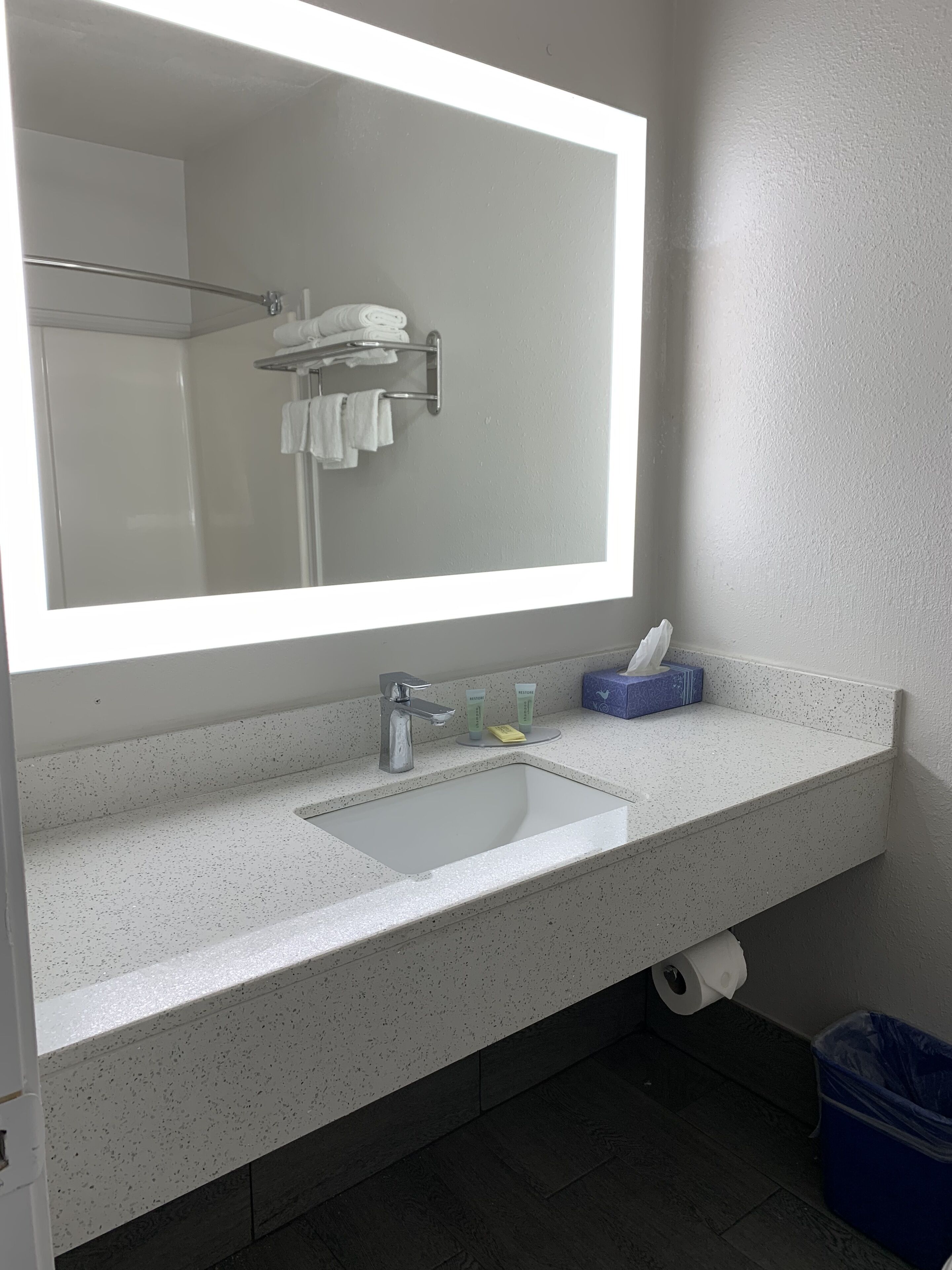 Ein Badezimmer mit großem Spiegel, Waschbecken und Pflegeprodukten sowie einer Dusche.