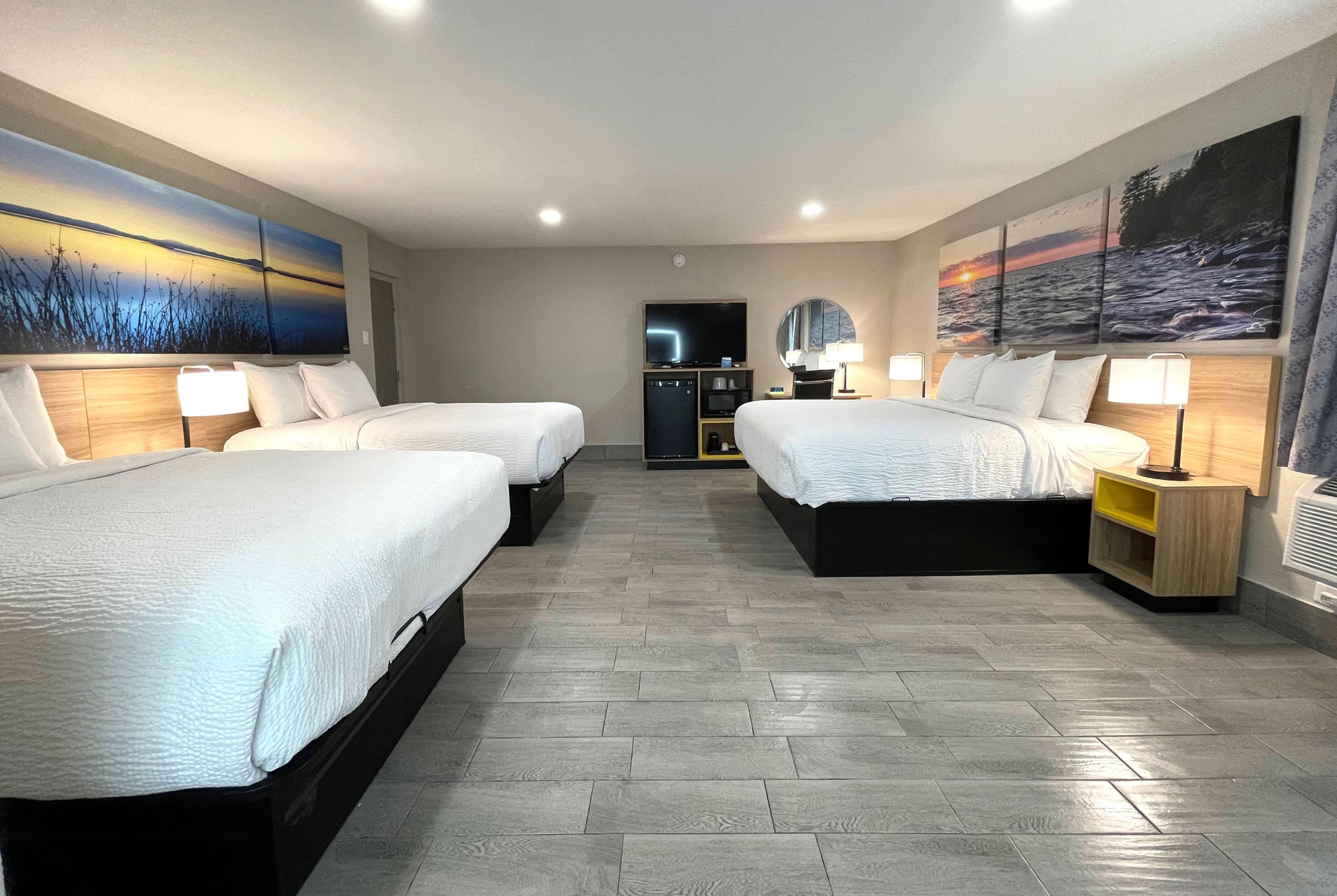 A hotel room with two beds, a TV, a desk, and a bathroom.