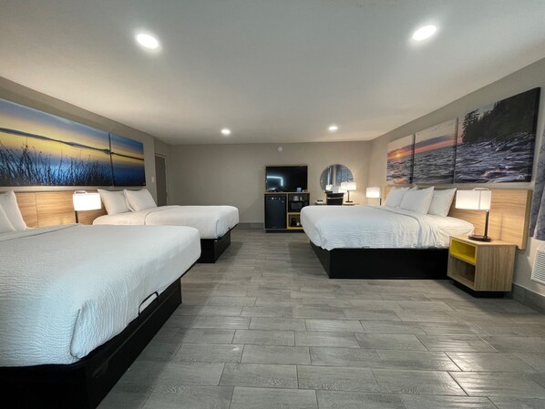 A hotel room with two beds, a TV, a desk, and artwork on the walls.