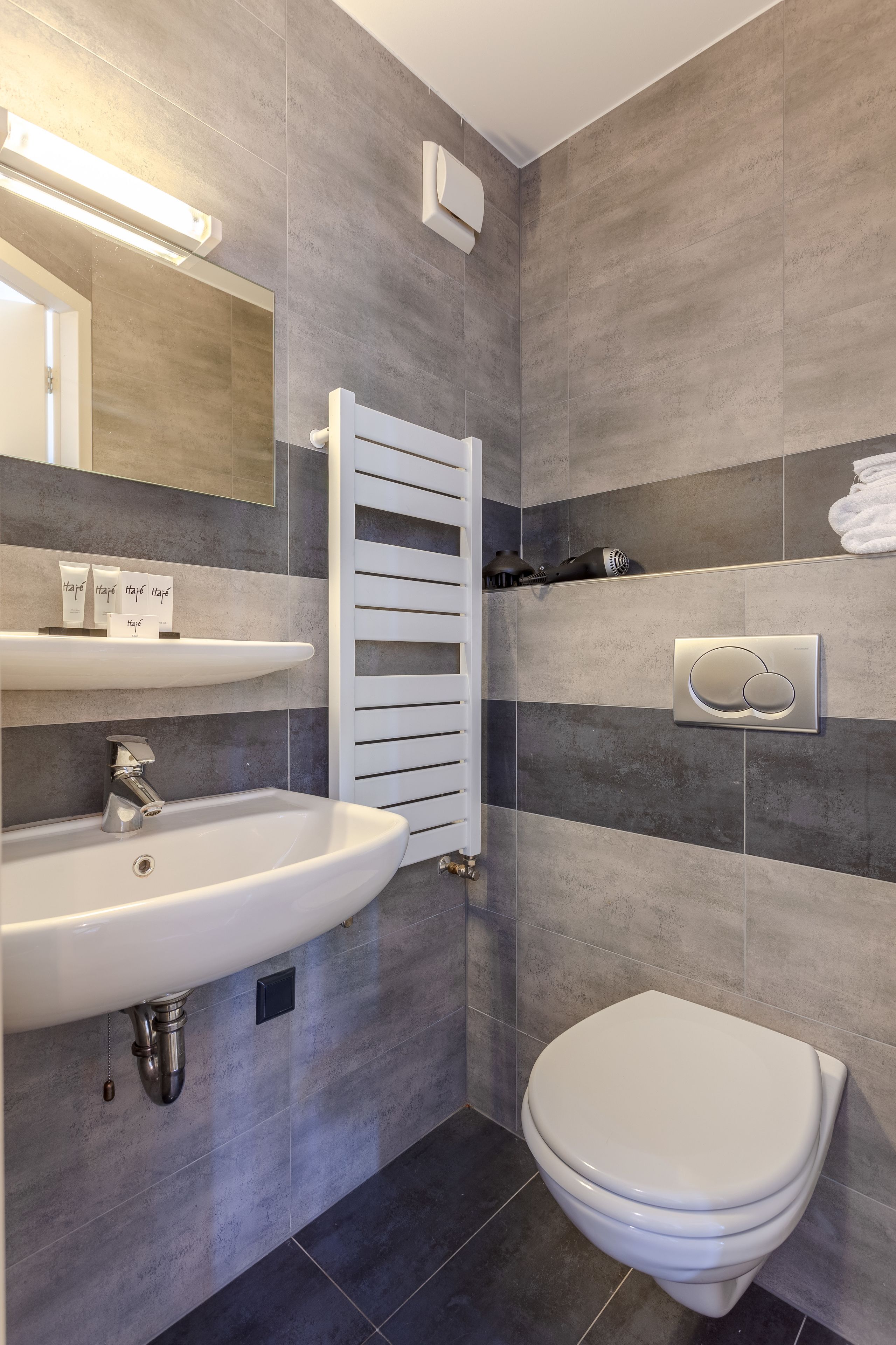 Un baño moderno con un lavamanos blanco, un inodoro y un perchero para toallas.