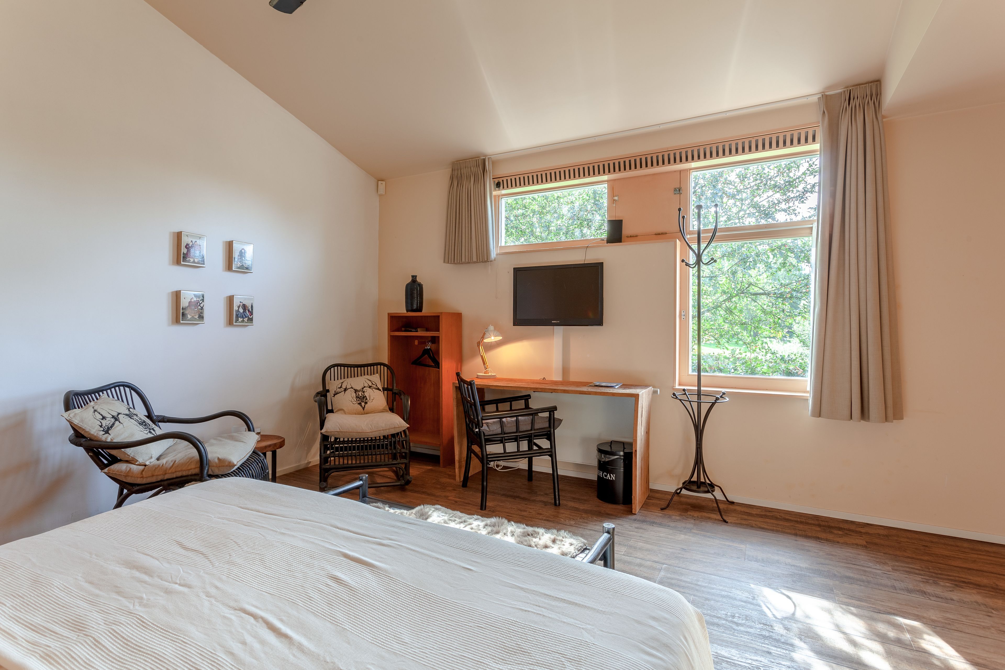 Un dormitorio con cama, escritorio, silla, televisor y ventana con cortinas.