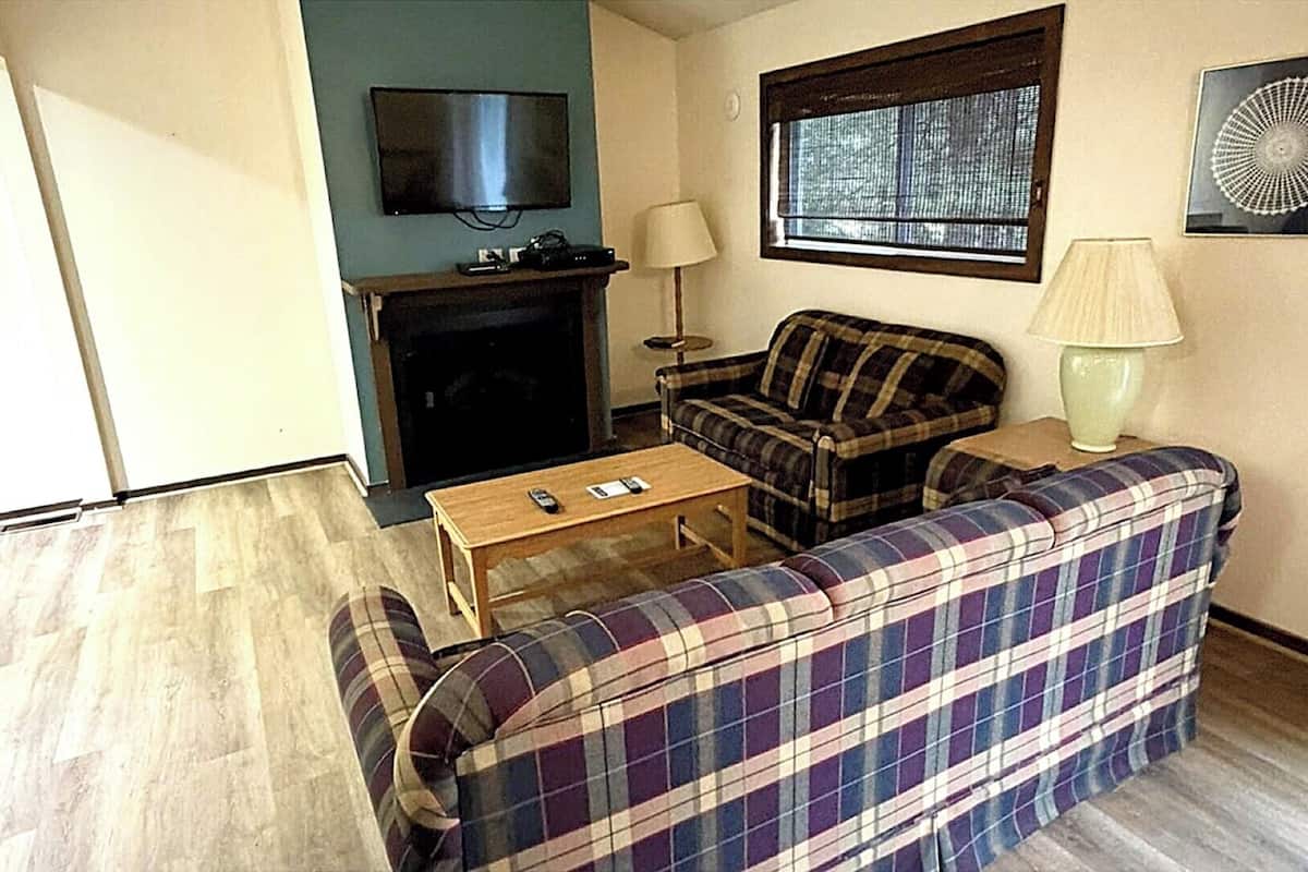 A living room with a sofa, a small table, a television, and a fireplace.
