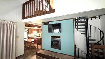 A compact kitchen with a built-in oven and microwave, a dining area with a table and chairs, and a staircase leading to an upper level.