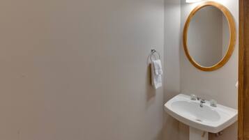 A bathroom with a white sink, a wooden-framed mirror, and a towel hanging on a metal ring.