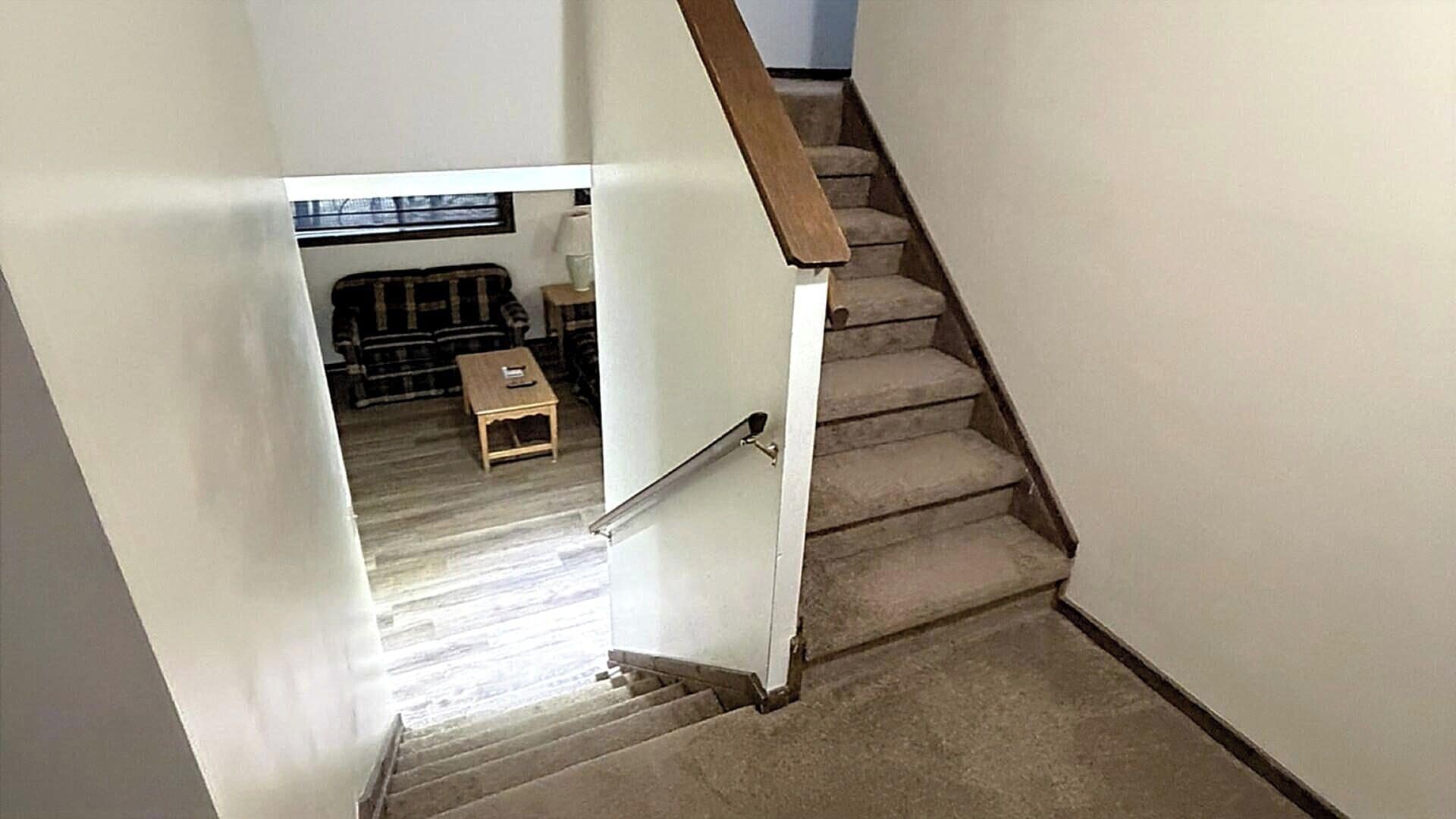 A staircase with a wooden handrail leading to a landing.