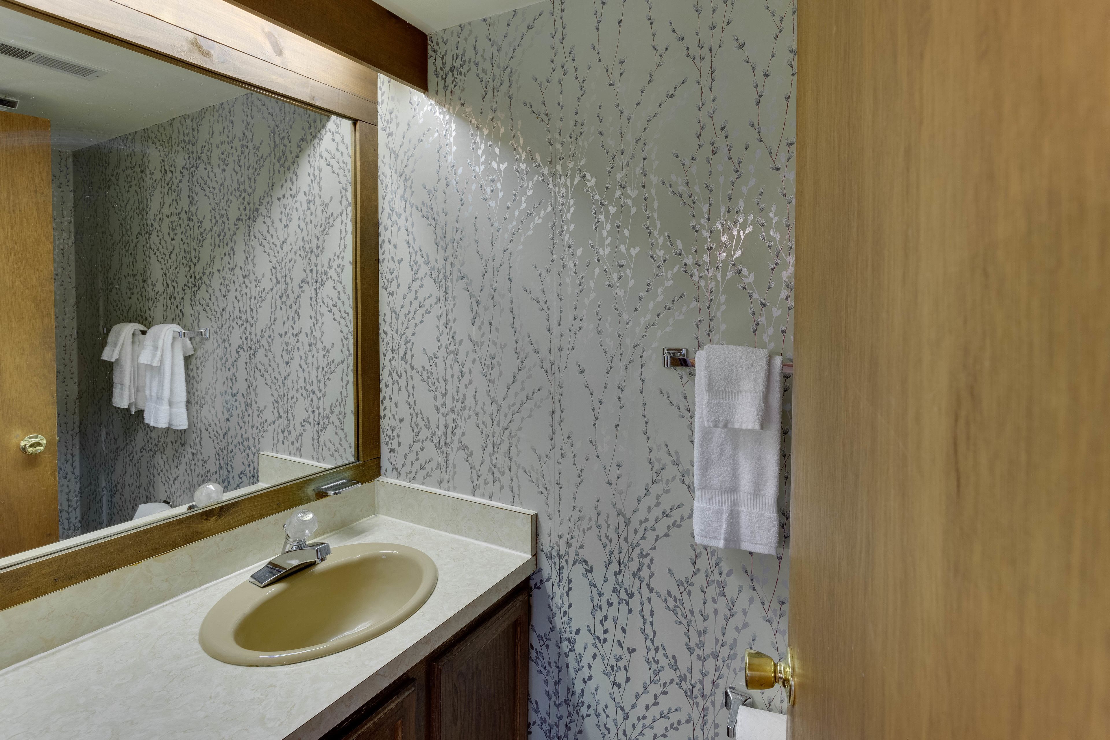 A bathroom with a sink, mirror, and wooden door.