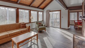 A spacious living room with a high ceiling, large windows, a sofa, a chair, and a dining area. - Chalet High by Coolvacay (Basye)