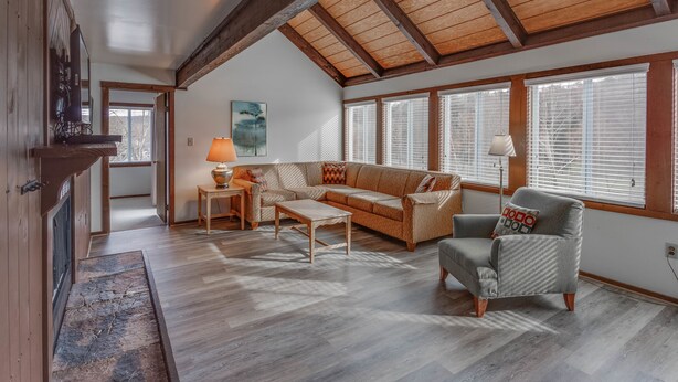 A spacious living room with a high ceiling, wooden beams, a sofa, a coffee table, and a fireplace. - Chalet High by Coolvacay (Basye)