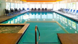 An indoor swimming pool with clear water, surrounded by lounge chairs and a sunlit interior. - Chalet High by Coolvacay (Basye)